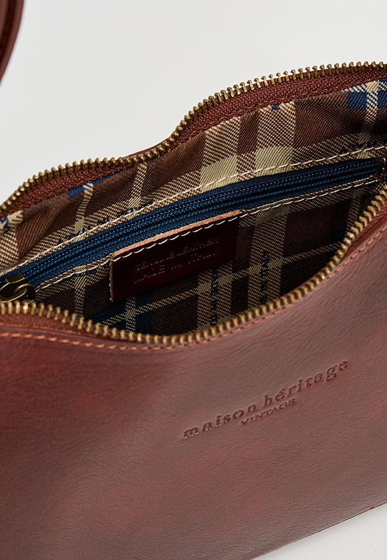 Braune Lederhandtasche mit Reißverschluss. Das Innere verfügt über ein karriertes Futter in Beige und Blau, mit einer kleinen navyblauen Reißverschlusstasche. Logo auf der Außenseite geprägt.