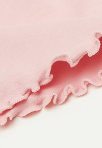 Rosa Stoff mit weicher Textur und einer gewellten Kante. Das Material wirkt leicht und dehnbar und zeigt eine glatte Oberfläche.