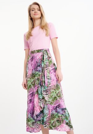 Top corto a maniche corte a coste di colore rosa abbinato a una lunga gonna voluminosa con stampa di foglie tropicali multicolore nei toni del rosa, verde e blu.