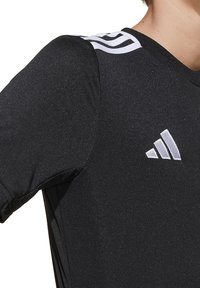 T-shirt de sport noir à manches courtes, fabriqué en tissu lisse. Présente le logo Adidas blanc et trois rayures blanches sur l'épaule.