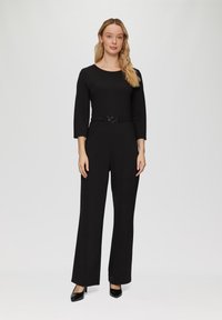 Zwarte jumpsuit met een aansluitende taille en driekwartmouwen, voorzien van een wijd pijpdesign en een ronde gesp riem. Glad stoffen textuur.