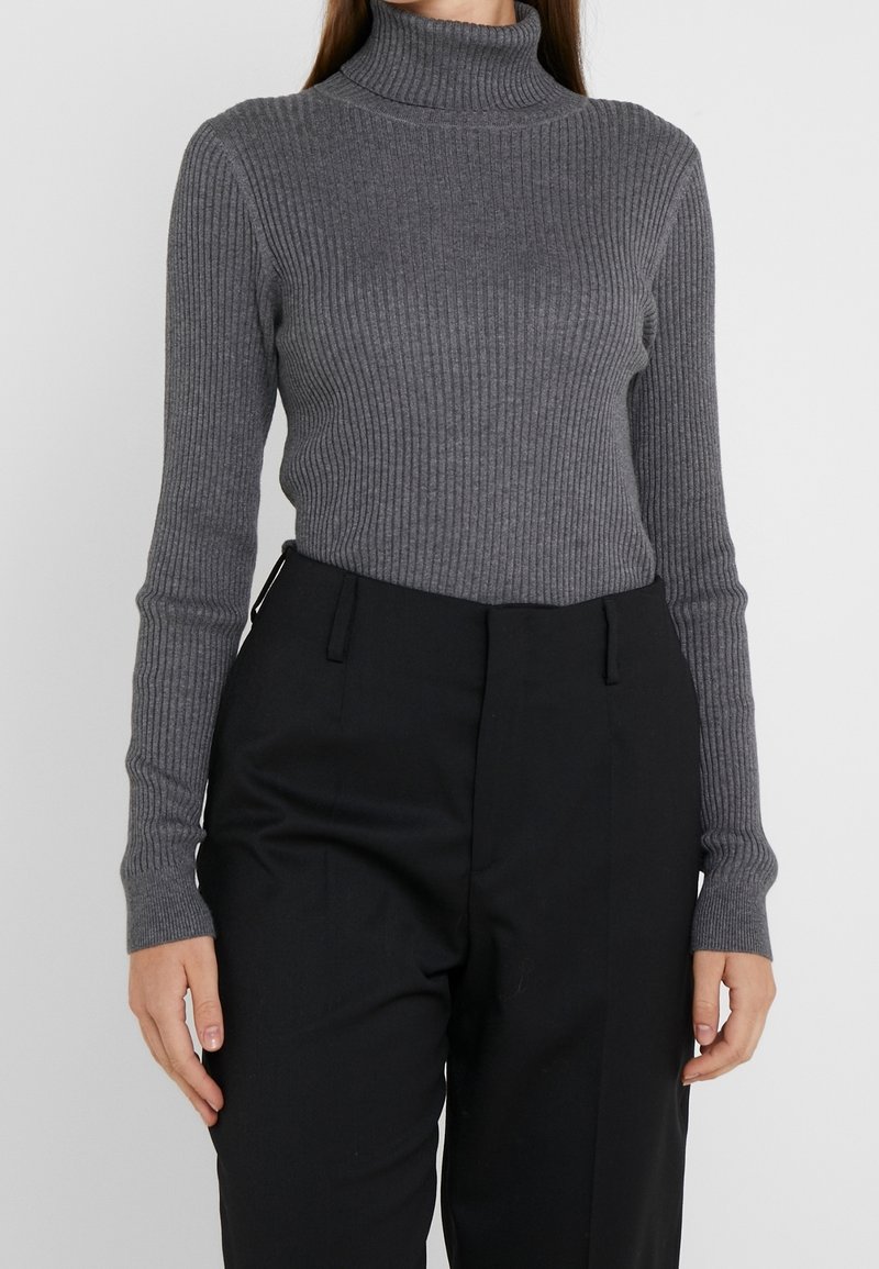 Grijze geribde coltrui met lange mouwen. Gemaakt van zachte stof. Gepaard met hoog-waist zwarte broeken, met een tailored ontwerp.