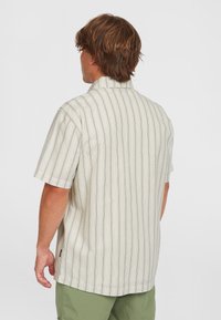 Short-sleeve shirt in light beige cotton with vertical gray stripes. Features a classic collar and relaxed fit, visible stitching at the hem.