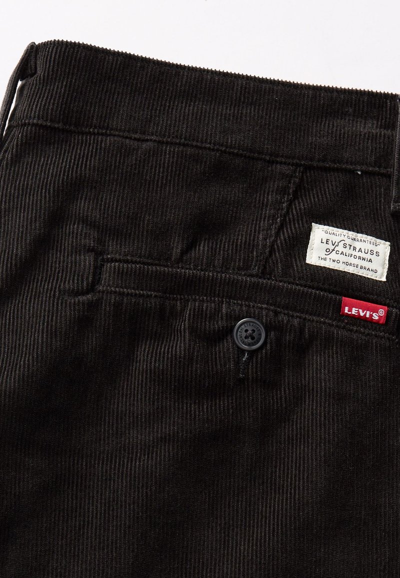Czarne spodnie z sztruksu z pionowymi prążkami, przednią kieszenią i czarnym guzikiem. Metka z napisem "Levi's" i "Levi Strauss & Co."
