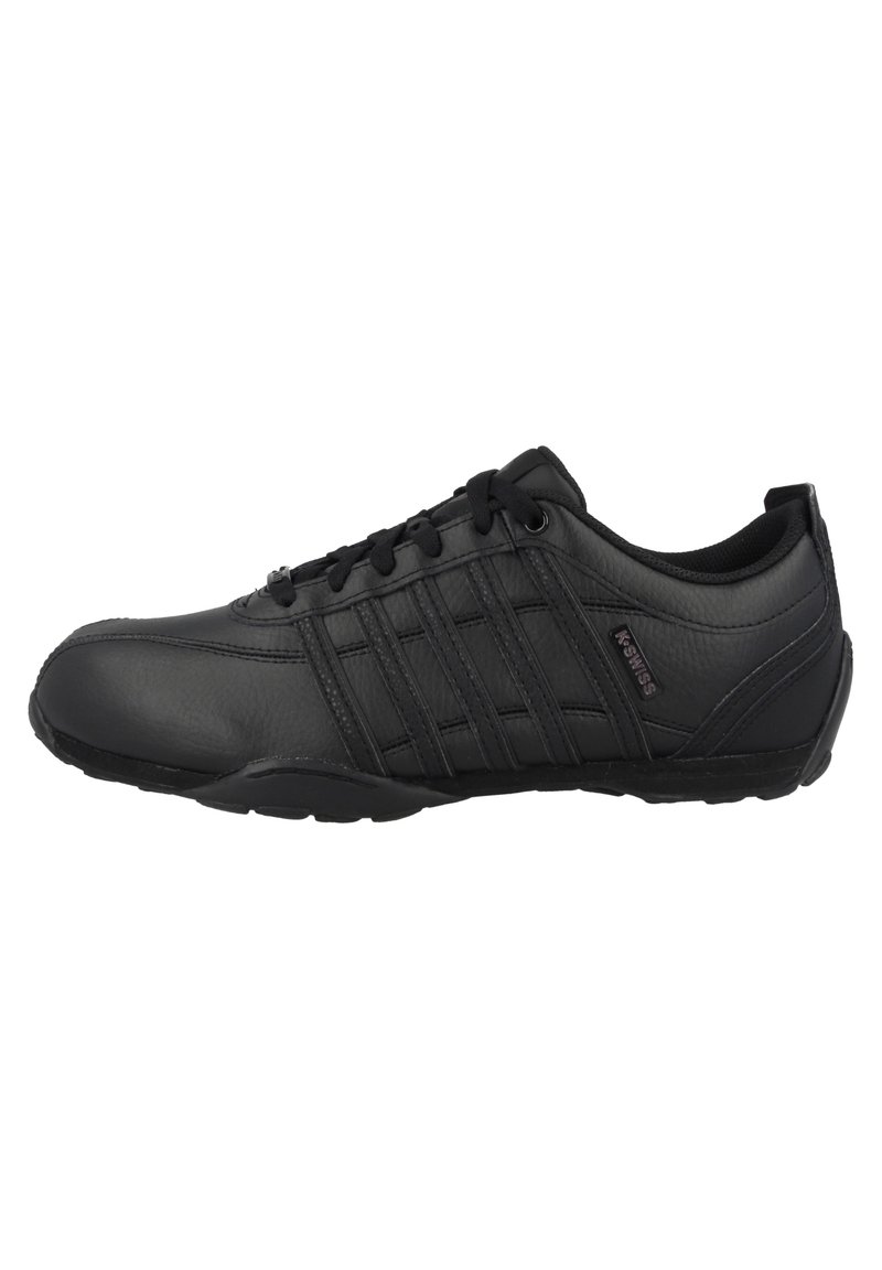 Chaussure de sport noire en cuir lisse avec un bout rond, un laçage, un col rembourré et plusieurs bandes parallèles sur les côtés.