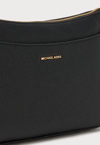 Juodas akmenuotas odinis krepšys su lygiu užtrauktuku ir įspaustu auksiniu „MICHAEL KORS“ logotipu priekyje. Stačiakampio formos su tekstūruotu paviršiumi.