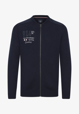 Námořnický svetr na zip s ribkovanou strukturou, zdobený vyšívanými detaily: "924 REG. TM," "VYSOKÝ VÝKON" a "Quebec."