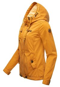 Žlutá bunda s kapucí, detaily na stažení a knoflíkovým zapínáním. Obsahuje dvě přední kapsy a nášivku s logem na rukávu. Měkká struktura.