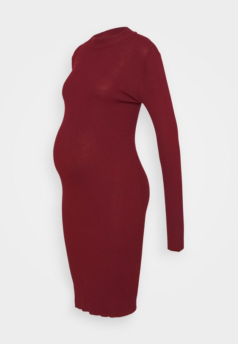 Robe de maternité près du corps en tricot côtelé rouge profond, avec manches longues et col montant, présentée sur un mannequin devant un fond blanc.