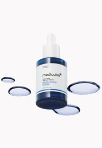 Niebieska szklana butelka z serum z białą pipetą, oznaczona napisem "Zero Pore One Day Serum", otoczona czterema okrągłymi niebieskimi kroplami żelu.