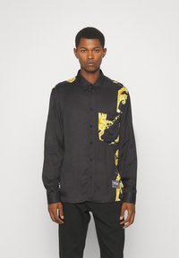 Zwarte button-up shirt van gladde stof, met gouden decoratieve patronen op één schouder en op de zak. Perfecte pasvorm met lange mouwen.