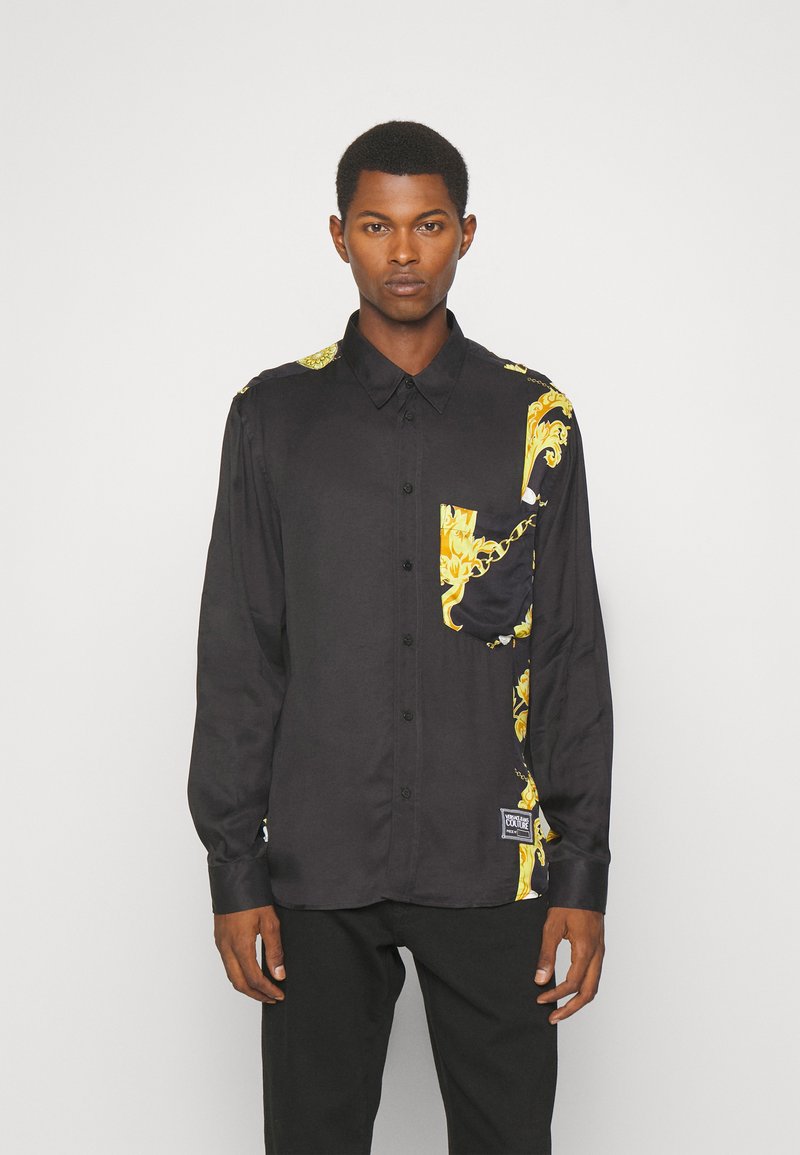 Zwarte button-up shirt van gladde stof, met gouden decoratieve patronen op één schouder en op de zak. Perfecte pasvorm met lange mouwen.