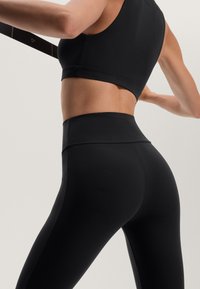 Fekete sportos crop top és magas derekú leggings sima, rugalmas anyagból. Minimális varrásokkal és diszkrét márkázási részletekkel rendelkezik.