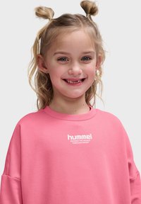 Rosa sweatshirt med rund hals och nedhasade axlar, med vit "hummel" logotyp och slogan. Slät textur, lös passform.