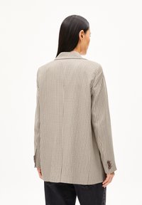 Beige checkered blazer with a tailored shape, notched lapels, and buttoned cuffs. Fabric features a subtle texture for visual interest.