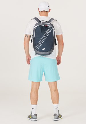 Grå og sort rygsæk med "Babolat"-logo, justerbare stropper, sidelommer og en lynlåslomme foran, lavet af et glat, holdbart stof.