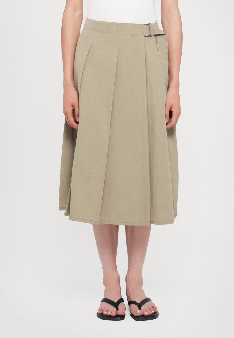 O fustă midi khaki cu un design plisat, talie plată și detaliu cu cataramă pe lateral. Fabricată dintr-un material ușor.