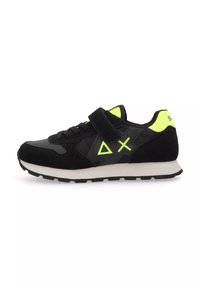 Scarpa da ginnastica nera realizzata in materiali scamosciati e sintetici, con una fascia in velcro, dettagli in verde brillante e una suola intermedia bianca.