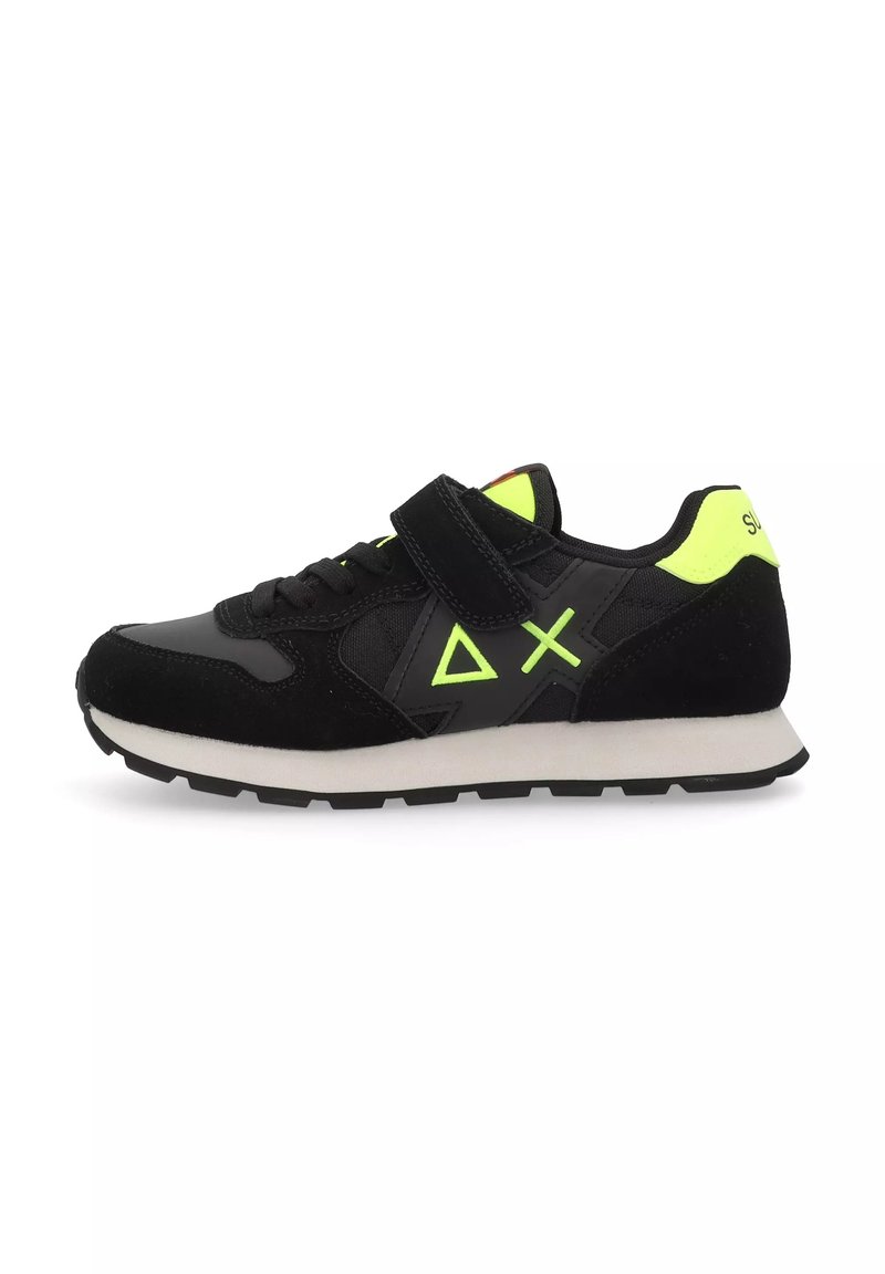 Scarpa da ginnastica nera realizzata in materiali scamosciati e sintetici, con una fascia in velcro, dettagli in verde brillante e una suola intermedia bianca.