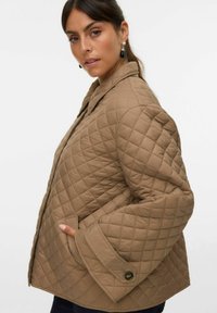 Veste matelassée marron avec un col, des manches longues, des poches avant et des détails en boutons, confectionnée dans un tissu lisse et léger.