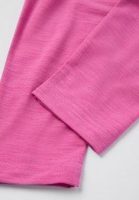 Läheltä otettu kuva taitetusta vaaleanpunaisesta kankaasta, joka näyttää hienoa rakennetta ja kaksoisompeleita sileässä, kevyessä materiaalissa.