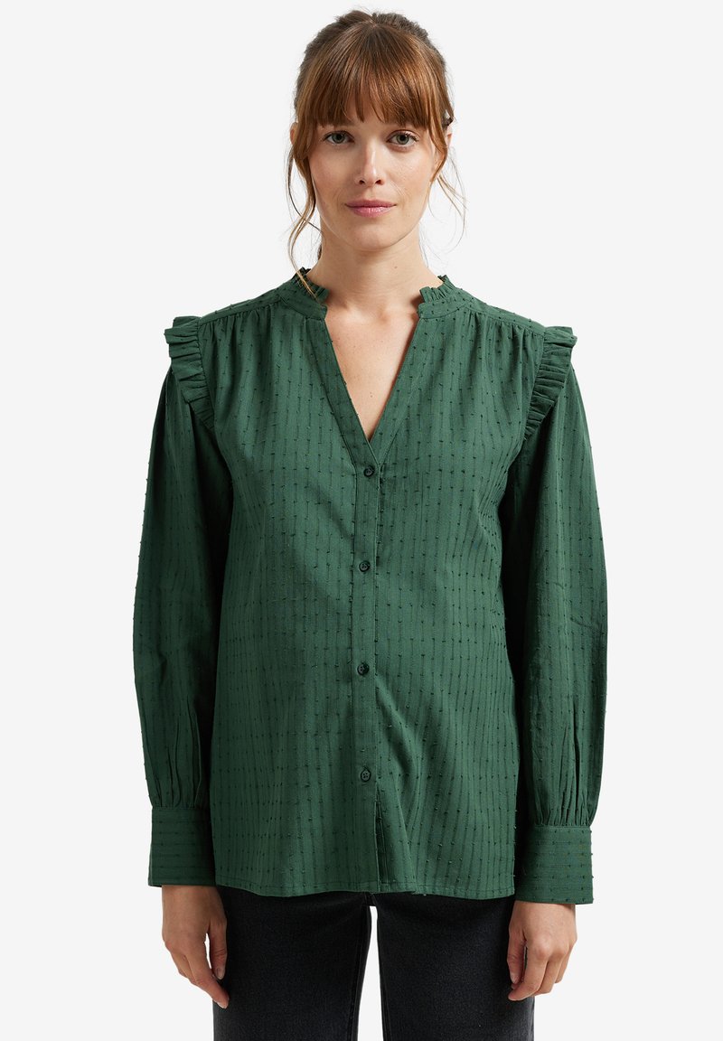 Green button-up shirt with a textured pattern, ruffled shoulders, and long sleeves. Features a V-neckline and relaxed fit.