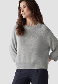 Helles graues Strickpullover mit rundem Ausschnitt, Dreiviertelärmeln und lockerer Passform. Besitzt einen strukturierten Stoff und einen gerippten Saum.