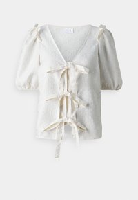 Blusa bianca in jacquard con maniche a palloncino e tre fiocchi in tessuto frontali, scollo a V e sottile motivo floreale.