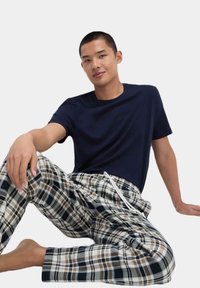 Marineblå bomulds t-shirt kombineret med brede ternede pyjamabukser i beige, brun og navy, med elastisk talje og snor.