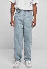 Light blue denim jeans with a relaxed fit, featuring a button closure, belt loops, and side pockets. Paired with white sneakers.