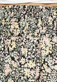 Tecido preto com um padrão floral em tons de amarelo e rosa. Apresenta uma cintura franzida e um material suave e texturizado com pregas.