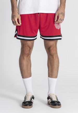 Shorts de sport rouges avec des rayures noires et blanches, en tissu texturé, avec un logo blanc décoratif sur le côté gauche.