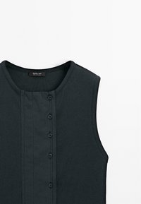 Ærmeløs sort ribbet top med rund halsudskæring og lodret knapstolpe med seks sorte knapper ned midten foran.