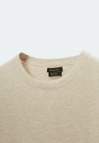 Beige, knitted sweater with a round neckline and textured pattern. Features a small label stating "Massimo Dutti" at the neck.