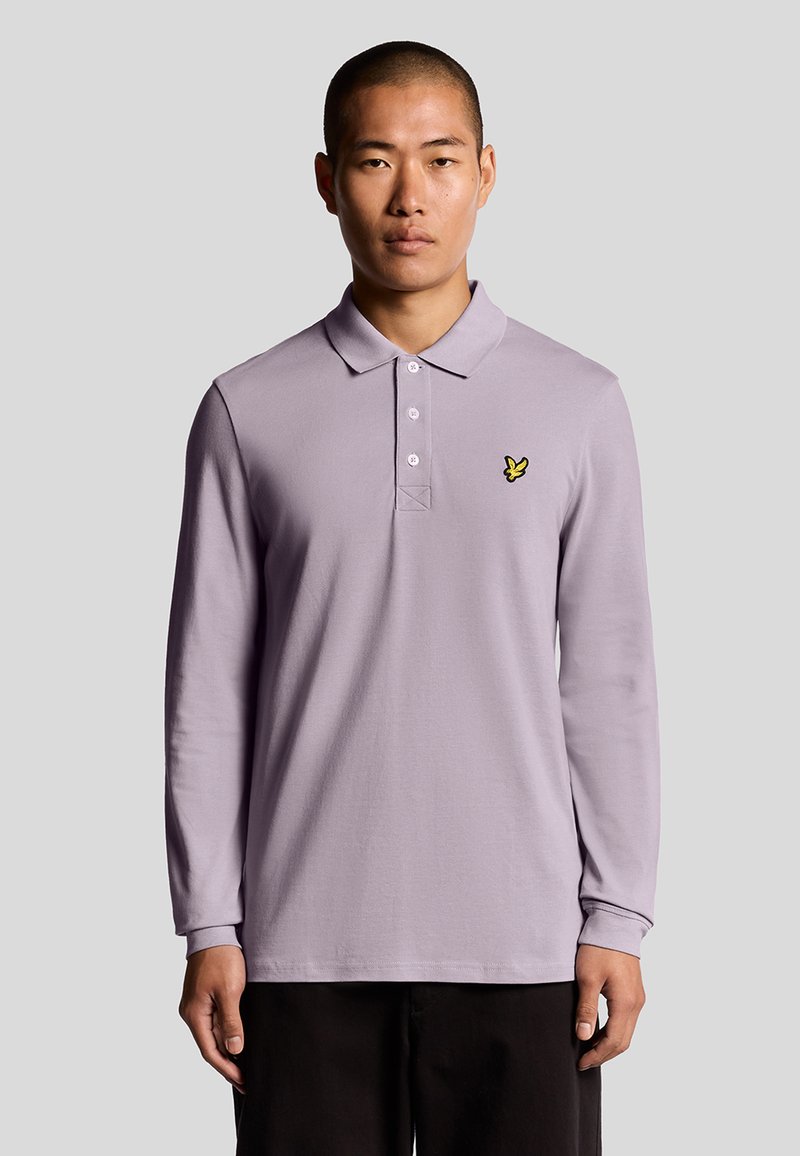 Polo a maniche lunghe di colore lilla in cotone, dotato di una chiusura con tre bottoni e un piccolo logo ricamato giallo sul petto.