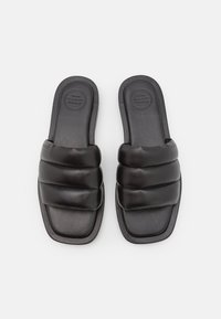 Sandali neri con una fascia elevata e imbottita. Realizzati in pelle, presentano una superficie liscia e una soletta di forma quadrata.