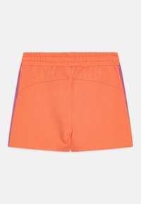 Short orange avec une finition texturée, doté d'un panneau latéral violet et d'une taille élastique pour le confort. Pas de logos ou de matériel visible.