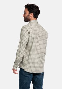 Herrenlangarmshirt in hellbeige mit Karomuster. Aus strukturiertem Stoff, mit einem klassischen Kragen und Knopfmanschetten.