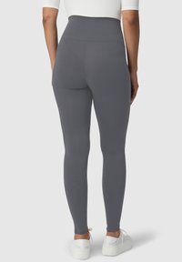 Szare legginsy z wysokim stanem wykonane z elastycznego materiału, dopasowany krój, gładka faktura, zestawione z białymi trampkami dla sportowego wyglądu.