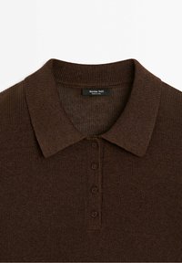 Ruskea neulottu pikeepaita, jossa on ribbireunus, neljä nappia ja teksturoitu muotoilu. Tunnuslukuna lukee "Massimo Dutti".