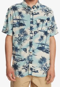 Camisa de manga corta con botones, presenta un fondo azul claro con patrones de palmeras y flores en azul oscuro. Incluye un bolsillo en el pecho y botones.