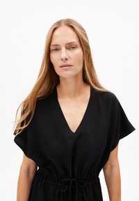 Schwarzes Leinenkleid mit kurzen Ärmeln und tiefem V-Ausschnitt. Verfügt über einen verstellbaren Kordelzug in der Taille für eine maßgeschneiderte Passform.