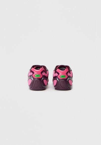 Une paire de chaussures de sport rose et violet foncé avec des étiquettes vertes "MARC" et "JACOBS" sur le talon, vues de l'arrière.