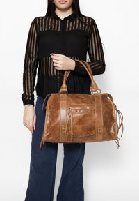 Borsa a tracolla in pelle marrone con finitura testurizzata, doppi manici e una tasca frontale con zip. Caratterizzata da hardware in tono oro e frange decorative.