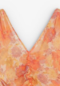 Tissu léger et transparent avec motif floral orange et jaune et un col en V à volants.