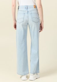 Jeans de piernas anchas de color azul claro con una cintura alta, dos bolsillos traseros con costuras en forma de onda y tela de denim texturizada.