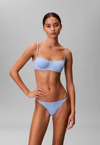 Conjunto de bikini azul claro que incluye un bralette estructurado con tirantes finos y braguitas a juego. Tela suave, diseño minimalista, detalles con marca.