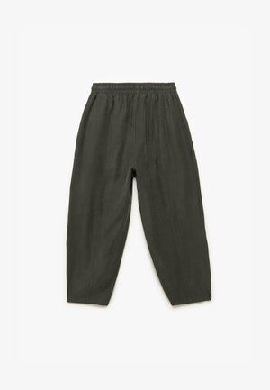 Tumman oliivinvihreät löysät housut, joissa on elastinen vyötärö ja ommellut pystysaumat, asetettuna tasaisesti valkoista taustaa vasten.