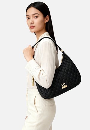 Borsa a tracolla in pelle nera trapuntata con dettaglio in metallo dorato e cerniera. Presenta una silhouette spaziosa e una texture morbida.