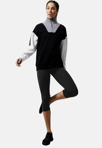 Kvartsdragkedja med långärmad tröja i svart och grått; parat med svarta capris. Har dragsko, subtil logotyp och en avslappnad passform.